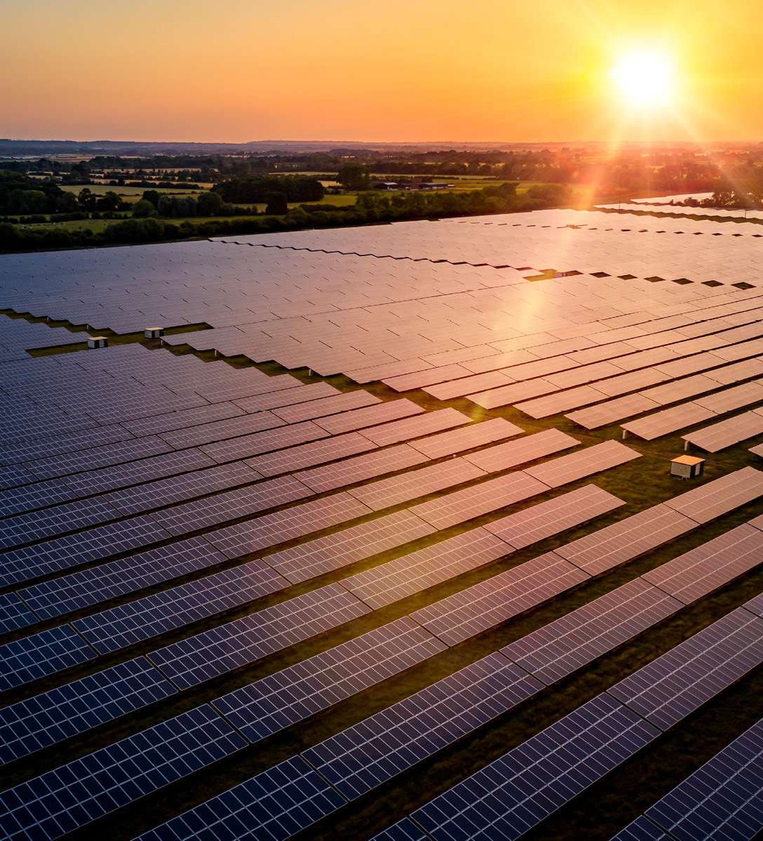 Sun setting over a field full of solar panels at a solar energy farm 